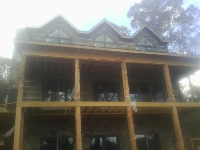 Dormers and porch framing on a large log home under construction — Roof Coating work by our crew in Belvue