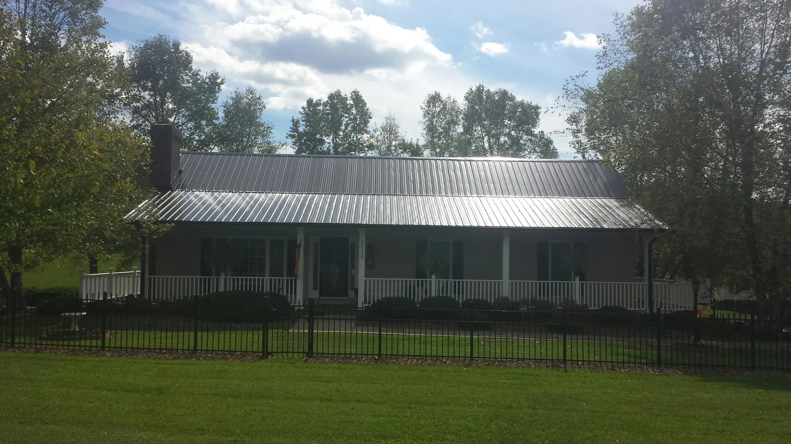 Gray metal roof on a brick ranch with a full width front porch — Gutter Guard Installation work by our crew in Belvue