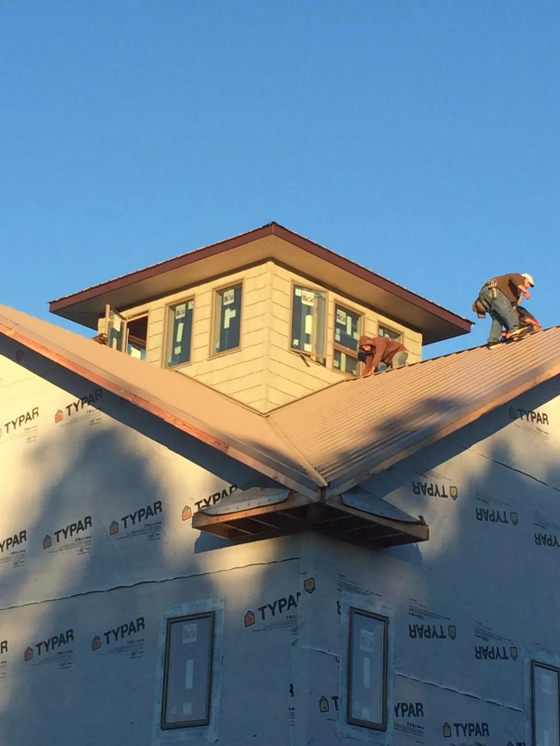Roofers working around a rooftop cupola on a new metal roof at sunset — Roof Waterproofing in Belvue by Roofing Brothers